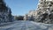 View through the windshield of a car driving on a slippery road in the forest after a snowfall.