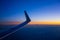 View of the wing of an airplane before dawn. Mountains and a peak are visible in the distance