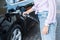 View of woman holding fuel pump while refueling black car with benzine