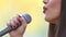 View of woman\'s mouth with red lipstick, smiling and singing with microphone