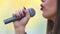 View of woman\'s mouth with red lipstick, smiling and singing with microphone