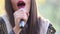 View of woman\'s mouth with red lipstick, smiling and singing with microphone