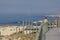 View of woman seat on wood bench in pedestrian wooden walkway, beach and sea as