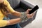 View of woman with tied hands with metal chain holding smartphone on sofa