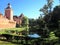 View of a wooden bridge over a moat with water, the spire of the town hall, a medieval castle with towers