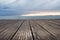 View of wooden decking, sea and gray sky at dusk.