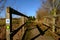 View of a wooden framed public footbridge seen at the side of a circular walk in a rural location.