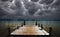 View on wooden pier to water with  menacing deep dark storm clouds