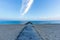 A view of a wooden ponton on a sandy beach with stony groyne breakwater and calm beautiful sea in the background at blue hour