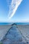 A view of a wooden ponton on a sandy beach with stony groyne breakwater and calm beautiful sea in the background at blue hour