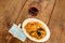 View of wooden table, plate of paella and glass of red wine, with protection mask with antibacterial gel, new normal in restaurant