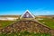 View on  wooden turf house built on pile of natural stones against blue sky-