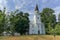 A view of a wooden white church surrounded by trees