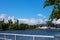 View of the yacht mooring near the river bank against the background of houses and the blue sky with clouds from the dock of the