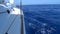 A view from the yacht`s deck to the bow and sails, close-up.S ide view with blue sea and waves.