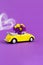 View of a yellow convertible car with a bouquet of flowers on a purple background behind which a train of a white heart develops.
