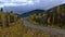 View of Yellowhead Highway (16) between forest with yellow trees in autumn near McBride in Robson Valley, BC, Canada.