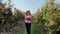 View of a Young female business farmer or agronomist working in the apple garden, makes notes on a tablet for better