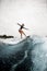 View on young sportive woman confidently stands on the wake surf board and rides the wave.