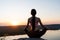 View of young woman exercising yoga at sunrise by the lake, people meditation serenity concept and wellbeing in life