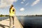 View of young woman running on dock by river in morning. Health conscious concept