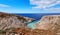 View of z-shaped bay, blue sky, beautiful clouds, sunny day, azure sea. Red soil in foreground. Stefanou beach, Seitan