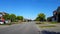 Viewpoint of Man Walking His Dog at City Suburb Four-Way Stop Sign Intersection Road With Traffic in Day.  Dog Walker Person