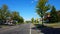 Viewpoint of suburban city street with vehicle traffic. Urban road along residential suburb houses during day