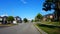 Viewpoint of Suburban City Street With Vehicle Traffic.  Urban Road Along Residential Suburb Houses During Day