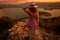 Viewpoints to capture memorable sunsets. Young woman in colorful dress and hat standing upright and watching sunset of the city of