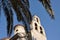 Views of bells through the leaves of palm trees on the Orthodox Church of the Holy Trinity