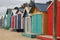 Views of rows of colourful beach bright painted summer holiday bathing box`s along a sandy beach on a sunny day, Brighton beach,