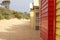 Views of rows of colourful beach bright painted summer holiday bathing box`s along a sandy beach on a sunny day, Brighton beach,