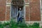 Viking warrior near an old brick castle . Sword and helmet. Pensive look. Old wooden door in the form of an arch