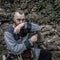 Viking warrior with thick beard sits thoughtfully in front of a stone wall