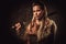 Viking woman with sword in a traditional warrior clothes, posing on a dark background.