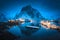 Village with boats on the sea at night and snowy mountains