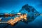 Village with boats on the sea at night and snowy mountains