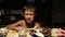 Village boy eating pancakes with wooden fork in an old house, old time