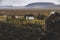 Village with farms in a rural area of the mountains of Iceland, with snowy mountains in the background