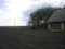 A village garden in a Russian village. Plowed land. Chernozem. There is a log shed next to the vegetable garden