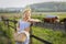 Village girl with a bag of milk and bread going through the fields with grazing cows. Summer rural life in Germany.