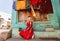 Village house and young woman sitting at front of colorful building in small indian town.