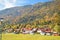 Village houses along the road against the background of mountains and forests in autumn in Alps