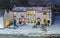 A village pub at night in the snow seen from above. The light are on and the glow looks warm and welcoming