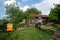 Village yard and beekeeper mowing tall grass in protective clothes