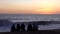 Vina del Mar, Chile - 2019-07-18 - five friends sit on beach watching sun set in front of rough surf