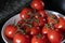 Vine ripe tomatoes in a white bowl on a granite counter