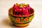 Vinegret Russian beet salad of boiled vegetables in painted wooden bowl on white table background.