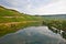 vineyards at the hills of the romantic river Mosel edge in summer with fresh grapes and reflection in the river